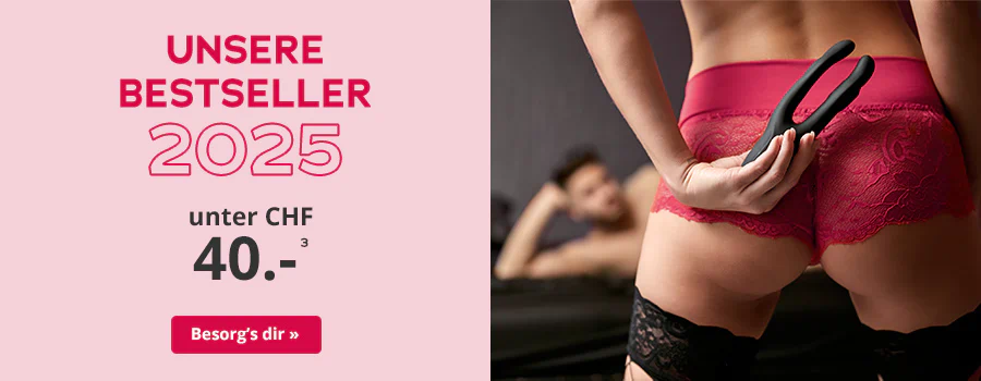 Frau in roter Spitzenunterwäsche hält ein schwarzes Toy hinter dem Rücken, im Hintergrund liegt ein Mann auf einem Bett. Text: 'Unsere Bestseller 2025 – unter CHF 40'. CTA: 'Besorg’s dir'