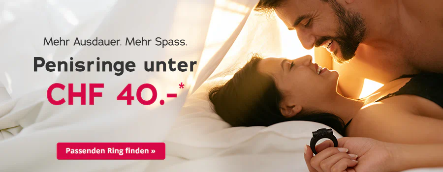 Ein lächelndes Paar liegt eng beieinander im Bett und schaut sich an. Die Frau hält einen schwarzen Penisring in der Hand. Links steht der Text „Mehr Ausdauer. Mehr Spass. Penisringe unter CHF 40.00*“ mit rotem Button „Passenden Ring finden ».