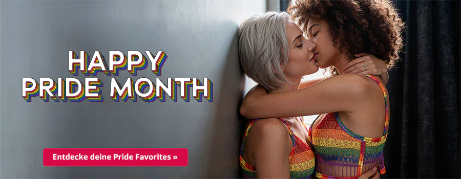 Zwei Frauen küssen sich eng umschlungen vor einem grauen Hintergrund. Eine hat silbernes, kurzes Haar, die andere lockiges braunes Haar. Sie tragen regenbogenfarbige Tops. Oben steht der Schriftzug „HAPPY PRIDE MONTH“, unten ein roter Button „Entdecke deine Pride Favorites ».